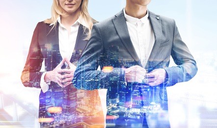 unrecognizable blond businesswoman and a businessman buttoning his suit are standing against a foggy city panorama. toned image, double exposure