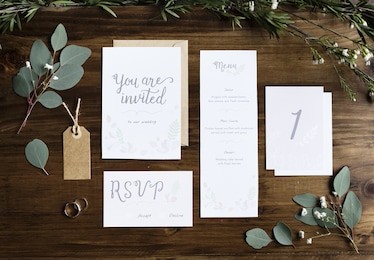wedding invitation cards papers laying on table decorate with leaves