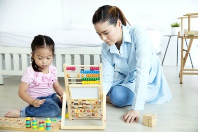 asian mother and daughter playing wooden toys in the bedroom