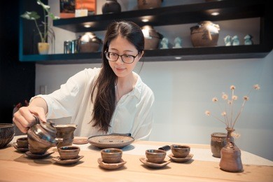 smiling elegant woman sitting on living room brewing champion traditional tea sharing with friends in afternoon tea time at home.