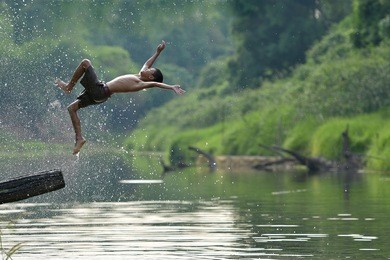 two asian boys are swimming on the river.