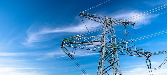 electricity pylon against blue cloudy sky