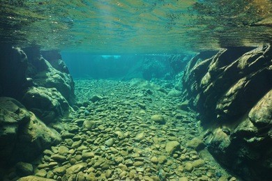 rocks and pebbles underwater in a river with clear freshwater, dumbea, new caledonia, south pacific