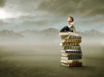 child sitting on a stack of books in a desert