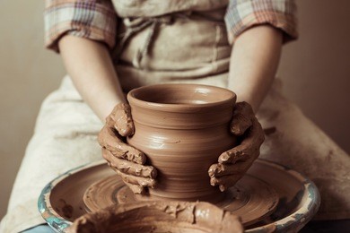 close up of child hands working on pottery wheel at workshop