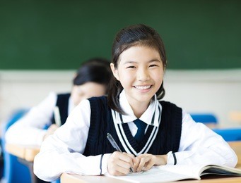 smiling student girl in classroom and her friends in background
