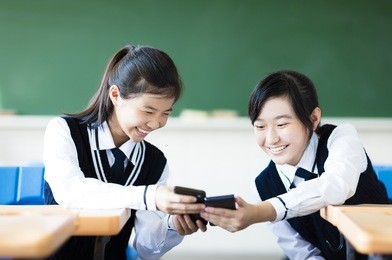 happy students girls watching the smart phone in classroom
