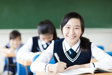 smiling student girl in classroom and her friends in background