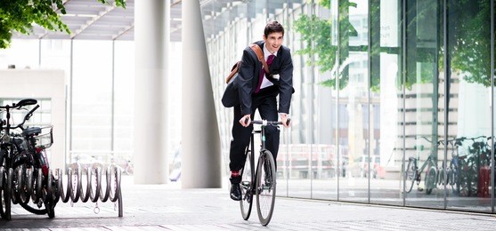 cheerful young employee with a healthy lifestyle riding an utility bicycle to a modern workplace in berlin