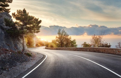 asphalt road. landscape with rocks, sunny sky with clouds and beautiful mountain road with a perfect asphalt at sunrise in summer. vintage toning. travel background. highway in european mountains