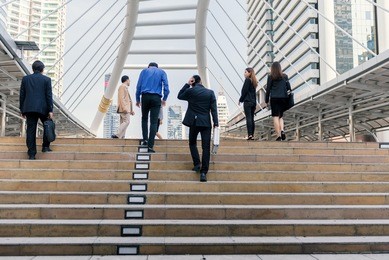 businessman and businesswoman up the stairs in rush hour to work. business people walking up stair in the city.