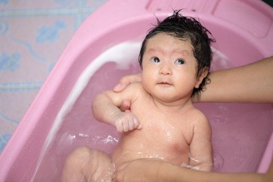 asian new born having a bath by mother