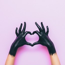 hands in black paint send heart. love and minimal fashion concept.