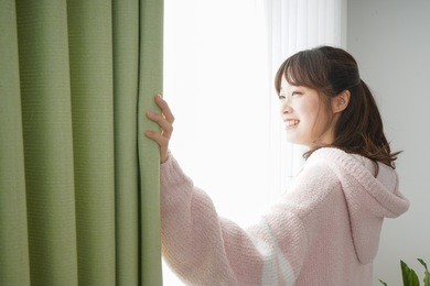 young woman opening a curtain when getting up 