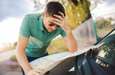 bad navigation. young man having a problem with orientation on the road during his journey with a car. he looking at map and try to find the missed road. traveling and transportation concept