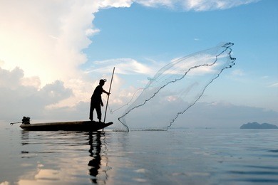 fisherman throwing fishing net during sunrise in pak pra village, phatthalung, thailand