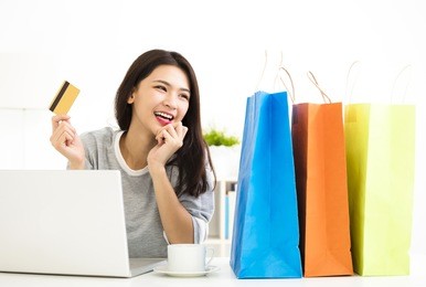 young woman showing credit card and shopping online