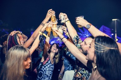 group of friends drinking beers enjoying music festival together