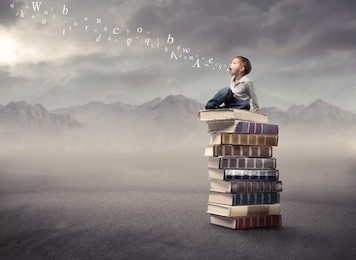 child sitting on a stack of books with letters coming out of his mouth