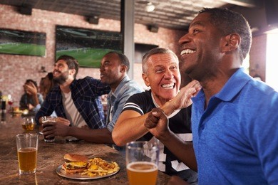 male friends in sports bar watch game and celebrate