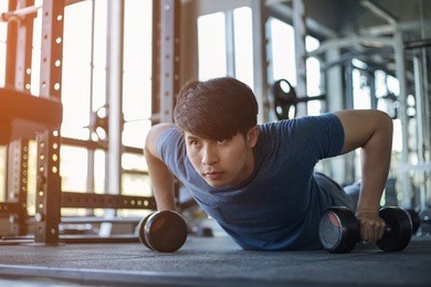 young asian man exercising in the fitness gym with flare light
