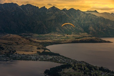 paragliding over queenstown and lake wakaitipu with the remarkables in the background from viewpoint at queenstown skyline, new zealand