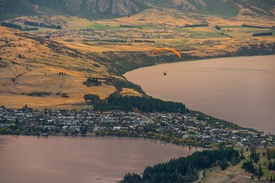 paragliding over queenstown and lake wakaitipu from viewpoint at queenstown skyline, new zealand