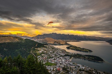paragliding over queenstown and lake wakaitipu with the remarkables in the background from viewpoint at queenstown skyline, new zealand