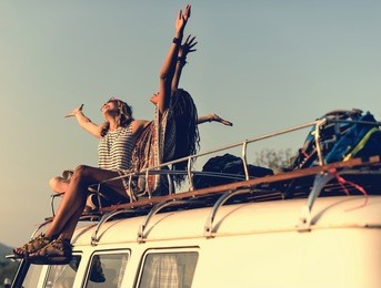 women sitting on the roof of the van traveling road trip