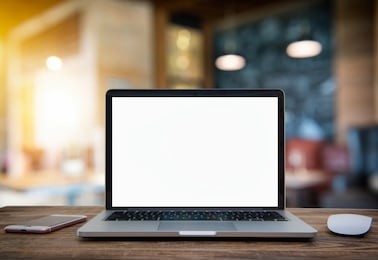 laptop with blank screen on table of coffee shop blur background with bokeh.