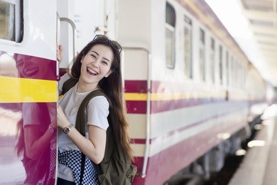 young asian cute woman is hanging and smiling at platform train station. travel summer concept.