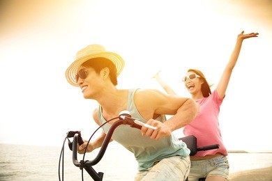 happy young couple riding bicycle on the beach