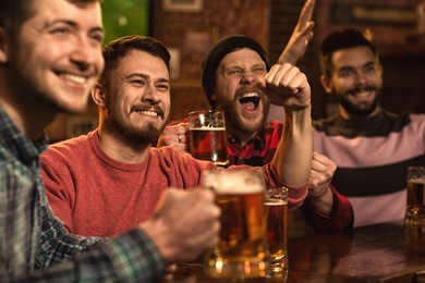 cheerful young handsome male friends having fun at the beer pub celebrating victory of their favorite team watching game on tv happiness people leisure entertainment bar restaurant friendship