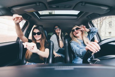 three girls driving in a convertible car and having fun