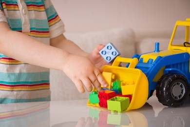 closeup of toddler boy's hands playing with colorful toy tractor. child playing with a car at a nursery or preschool. 