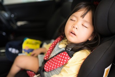transport, safety, childhood road trip and people concept - happy little girl sleeping in baby car seat, child in auto baby seat in car, adorable little girl in the car.