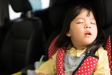 transport, safety, childhood road trip and people concept - happy little girl sleeping in baby car seat, child in auto baby seat in car, adorable little girl in the car.