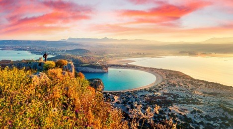 photographer take a picture of spring view of the voidokilia beach from navarino castle. great sunrise on the ionian sea, pylos town location, greece, europe. beauty of nature concept background.
