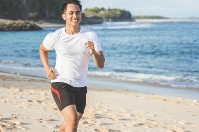 portrait of handsome asian man running on the beach
