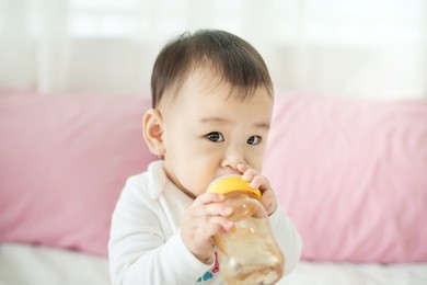 sweet baby girl sucking milk in bottle at home.