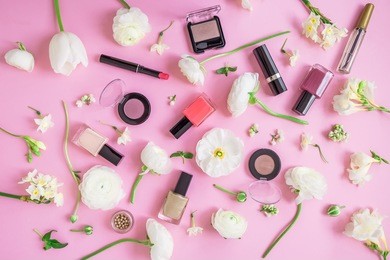 beauty concept. feminine desk with woman cosmetics and white flowers on pink background. flat lay, top view.