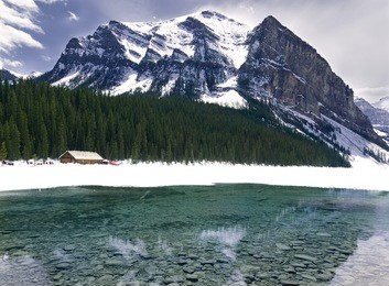 turquoise lake louise thawing in the spring with mountain backdrop     