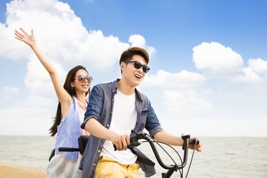 happy young couple riding bicycle on the beach