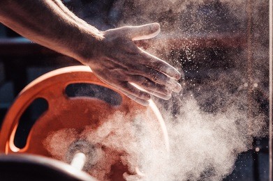 male powerlifter hand in talc and sports wristbands preparing to bench press. hands in chalk. with a barbell view