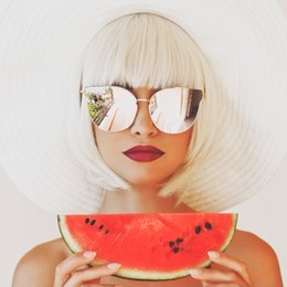 outdoor fashion photo of young beautiful lady in hat and sunglasses with watermelon. summer beach travel. summer vibes