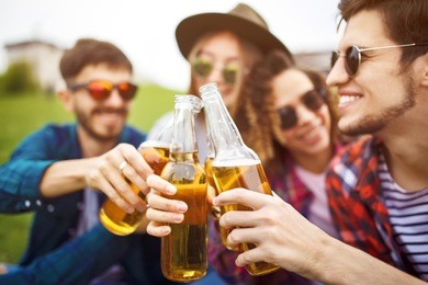 bottles of beer.group of friends enjoying party.people are drinking beer and laughing
.  the guy plays the guitar. everyone has a great mood. summer time. 
