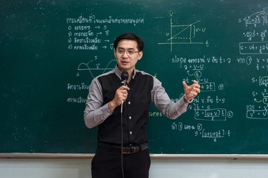 asian teacher giving lesson over the the physics formula in thai language on black board in school classroom, school education concept, the teacher wrote himself