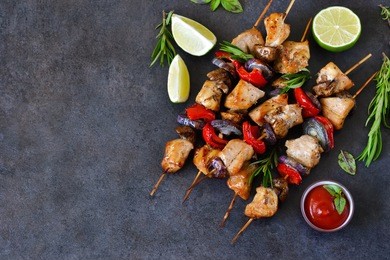 chicken kebab on skewers with mushrooms and peppers and barbecue sauce on a black background. food for a picnic.
