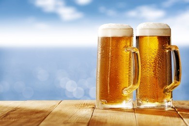 cold beer and summer day on beach with blurred landscape of sea 