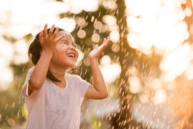 happy asian little girl having fun to play with the rain in vintage color tone